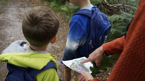 A family of two boys and their dad looking at a trail map for Dunwich Heath and Beach